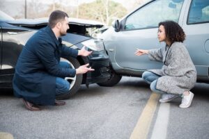 Driver explaining to young woman after bad car crash.