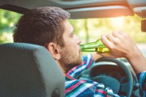 Man driving while drinking beer.