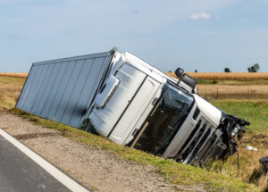 The large truck lies in a side ditch after the road accident.